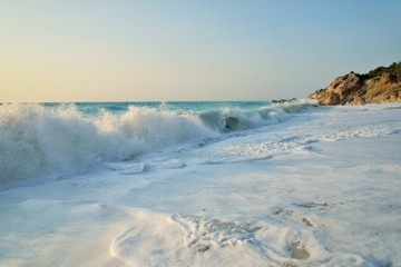 Fototapeta na wymiar Enormous waves crashing on the shore and on the rocks at the Megali Patra Beach at the sunset, Lefkada Island, Greece