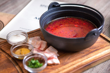 Borsch - traditional Ukrainian and Russian soup with red beets in ceramic bowl on wooden background
