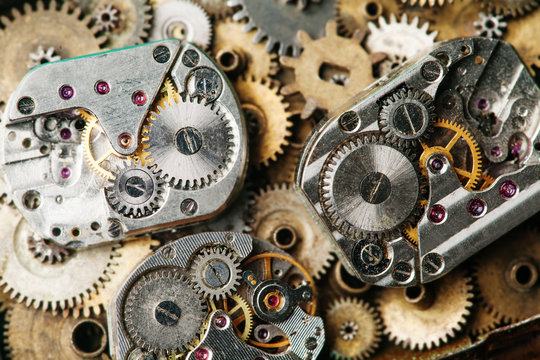 Vintage clocks mechanism close-up. Aged hand watches parts on bronze gears background