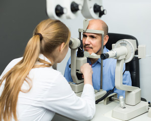 Fototapeta na wymiar female ophthalmologist and mature patient checking eyesight in clinic