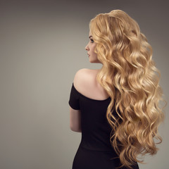 Blond woman with long curly beautiful hair. Back view.