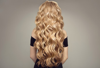 Blond woman with long curly beautiful hair. Back view.