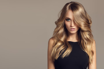 Blond woman with long curly beautiful hair. - obrazy, fototapety, plakaty