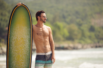 Surfer man with surfboard on sea coast.