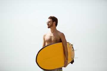 Surfer man with surfboard against sky background