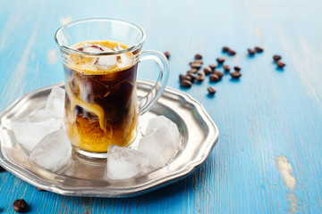 Refreshing iced coffee with cream over blue summer background
