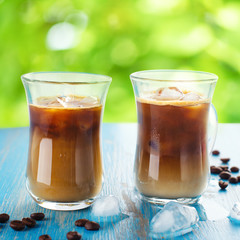 Iced coffee in a glass with cream over summer background