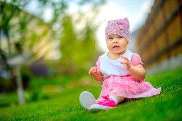 beautiful little baby sitting on the grass playing and having fun