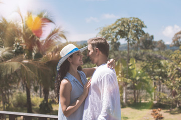 Young Couple Embracing On Summer Terrace Or Balcony Over Beautiful Tropical Landscape Background