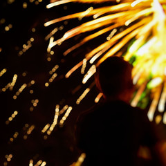 Abstract unrecognizable silhouette of boy back to us, who watches the show Fireworks. Explosive...