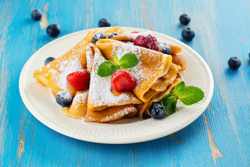 Crepes with jam, berries and sugar powder. Homemade pancakes, delicious breakfast