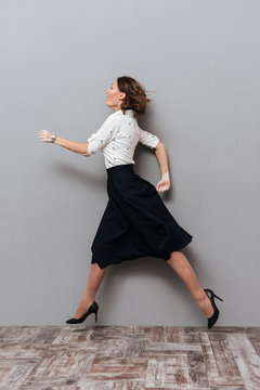 Vertical image of woman in business clothes running in studio