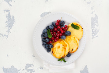 Cottage cheese pancakes syrniki with berries and honey on white background. Space for text