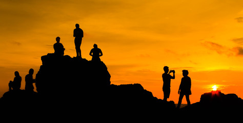 Asian tourists Waiting for sunset On a rock Golden sunlight on the sea and mountains,Nang Phaya Hill Scenic Point thailand