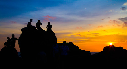 Fototapeta na wymiar Asian tourists Waiting for sunset On a rock Golden sunlight on the sea and mountains,Nang Phaya Hill Scenic Point thailand