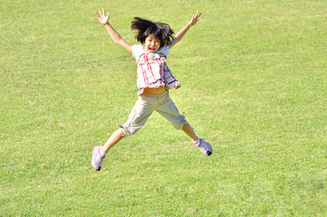 芝生広場でジャンプする女の子