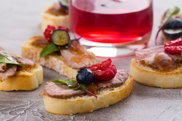 Bruschetta sandwiches with duck meat, fig sauce and berries on stone table. Space for text