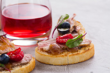 Bruschetta sandwiches with duck meat, fig sauce and berries on stone table. Space for text