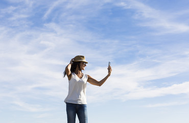 happy young woman taking a selfie with mobile phone at sunset. Summer. Fun and lifestyle