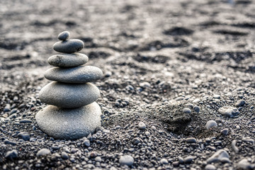Fototapeta na wymiar Stones stacked on top of a black beach in Iceland with copy space.