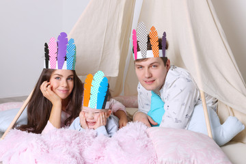Young father, mother, little son pose in wigwam with indian feathers in studio © singulyarra