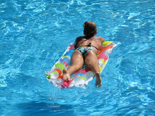 Slim girl in bikini on the mattress in the pool