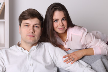 Young woman and man pose together on armchair in living room