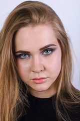 Young blonde in black clothes poses in white studio, close up