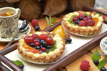 Tasty fruits tart with ripe raspberry, redcurrant, blackcurrant, kiwi, peach on long tray