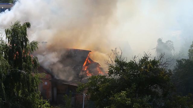 Large smoke puffs in a fire on the roof of an old house