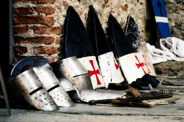 Medieval weapons, shields and helmets from the crusade age on a castle floor during an historical...