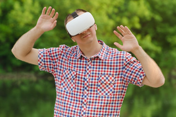 Man in helmet of virtual reality against the background of nature. Hands up