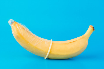 Condom and banana on a blue background close-up