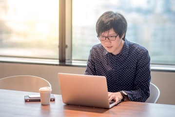 Young Asian businessman working with his laptop computer in office meeting room. entrepreneur and urban lifestyle concepts