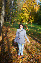 happy young teen girl in autumn scenery throwing leaves