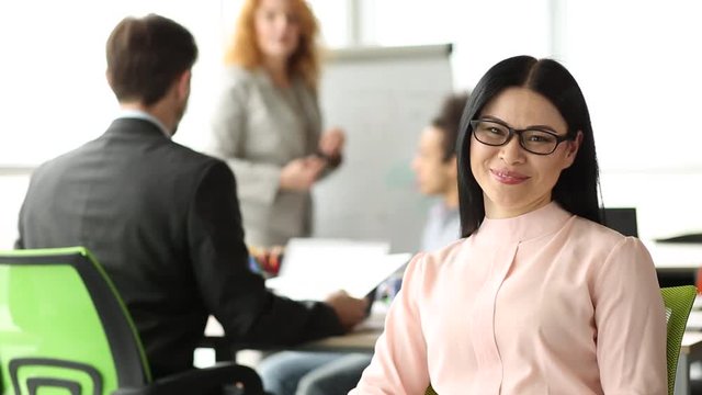 Close up view of attractive brunette businesswoman sitting in the meeting room. Beautiful lady in glasses during business discussion in the office.