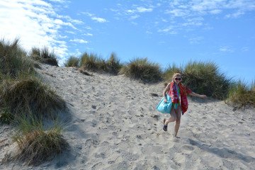 Mädchen mit Badesachen rennt die Sand Dünen runter