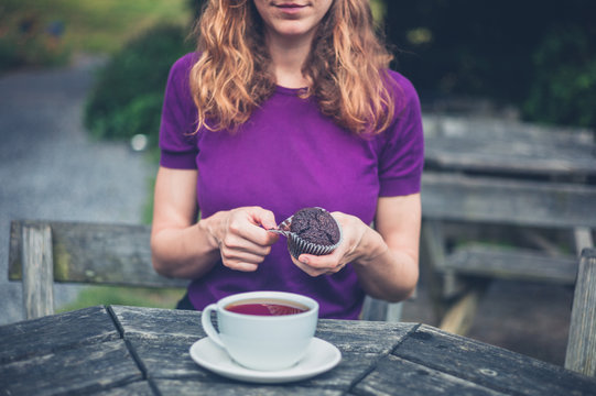 Woman with cup of tea and cupcake