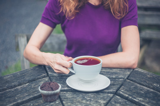 Woman with cup of tea and cupcake