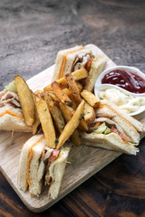 classic club sandwich with fries on wooden board