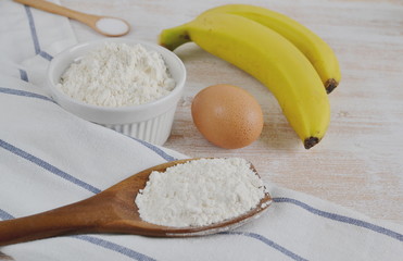Ingredients for Banana Pancakes Preparation Baking Accessories Kitchen Composition Wooden Table Top Metal Whisk Wooden Spoon Banana Eggs Milk