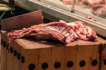 Ribs on a butcher block at a market with butchers knife