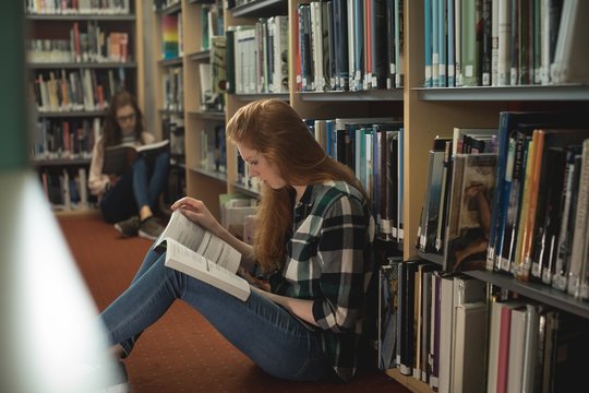 Female students reading book in library room