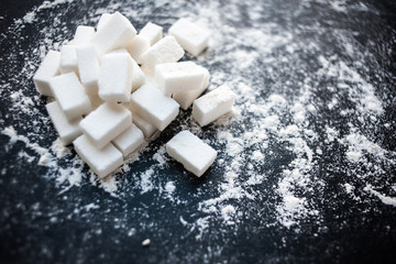 Unhealthy food concept - sugar  and flour on a black background. Dangerous high amount of sugar in food. Carbohydrates sources, top view.