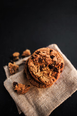 Chocolate chip cookie  on burlap and black slate background macro. Freshly baked choco cookie close up