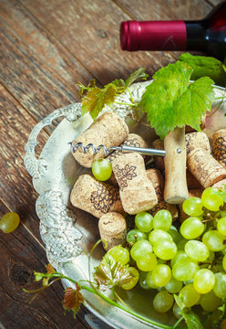 Grapes,a bottle of wine, corks and corkscrew on a wooden old table, rustic style
