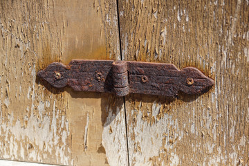 Aged shutters door board with iron decorated hinges and bolts.