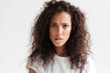 Upset young woman with curly hair looking at camera