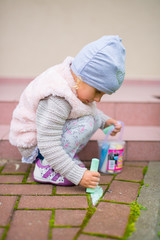 Dziewczynka malująca kredą na chodniku - obrazy, fototapety, plakaty