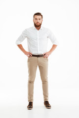 Fototapeta premium Serious young bearded man standing over white wall